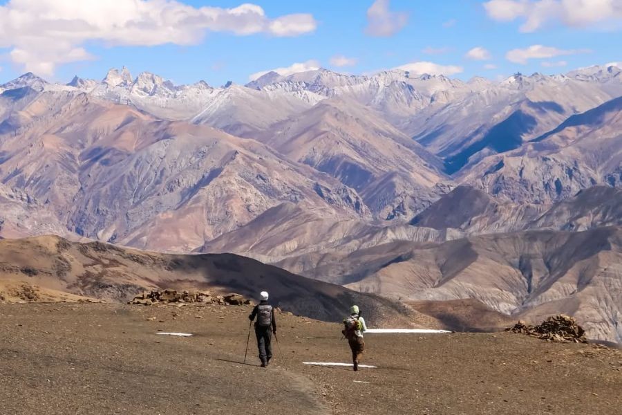 Two trekkers walking across high-altitude desert landscape in Upper Dolpo